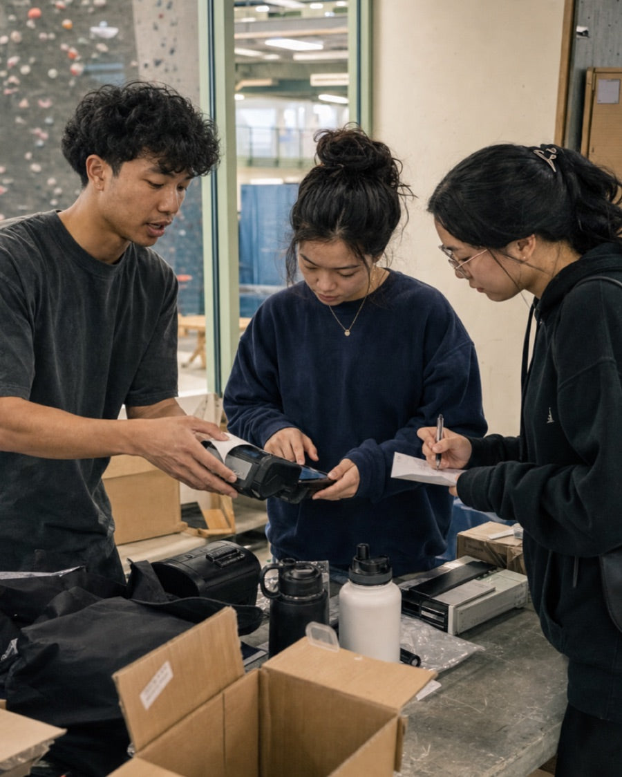 Young sales participants learning to use checkout equipment at a community event